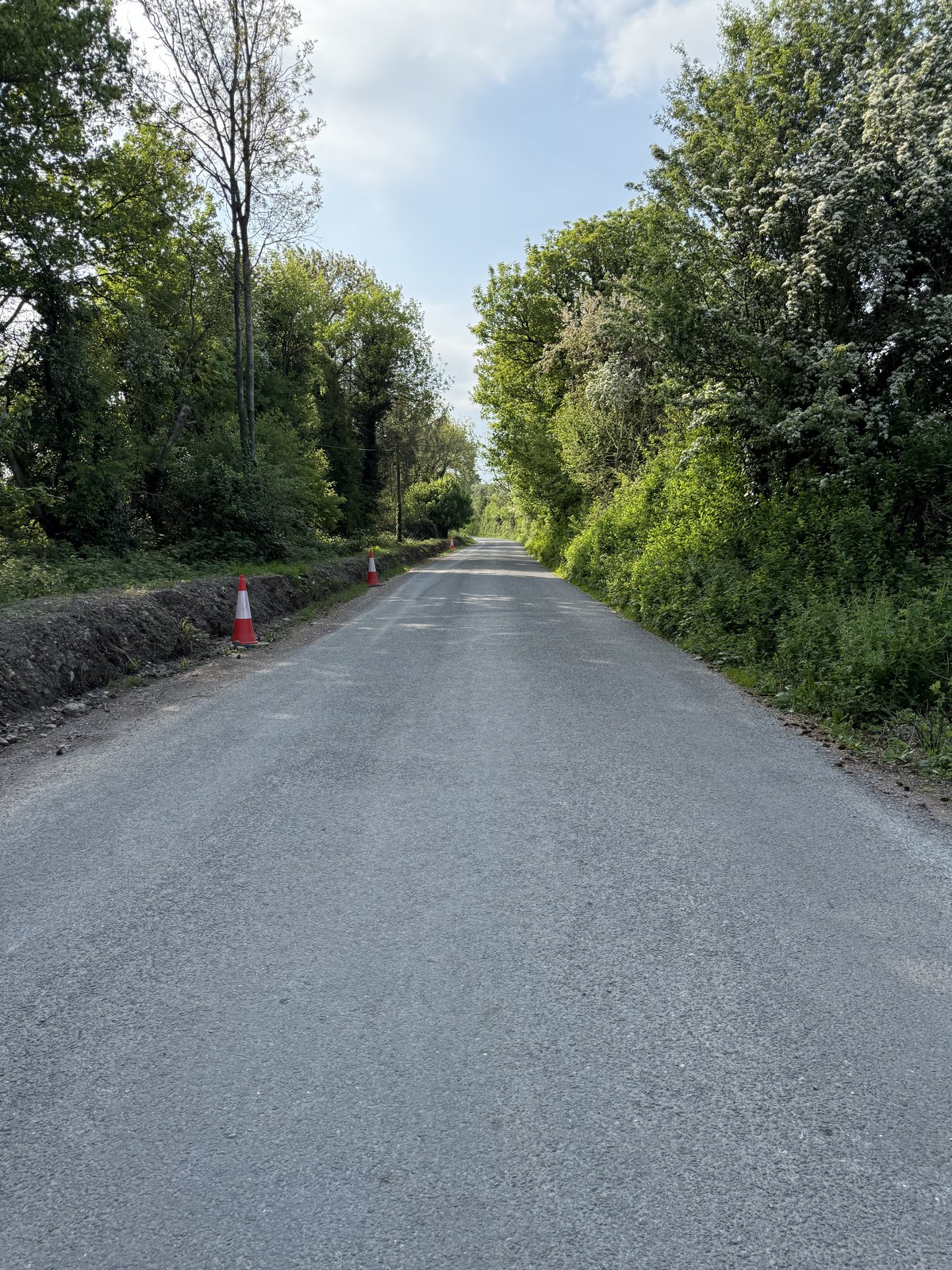The raised roadside verge along the approach, with traffic cones visible beside it