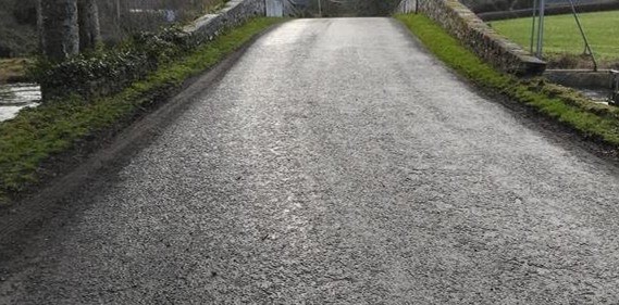 Over the crest of the humpback bridge — the lowered, grassed-over wall on the left.