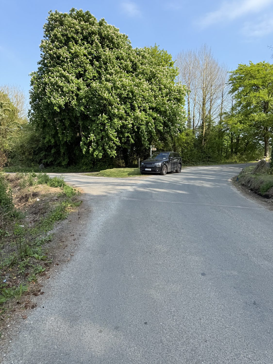 The wide approach and blind turn toward the bridge, with no signage of any kind